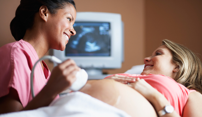 A clinician administering an ultrasound to a pregnant patient.