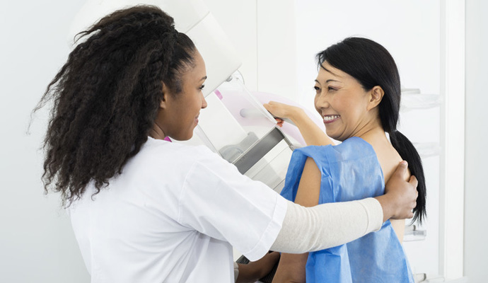 A clinician helping a patient in a mammography machine..